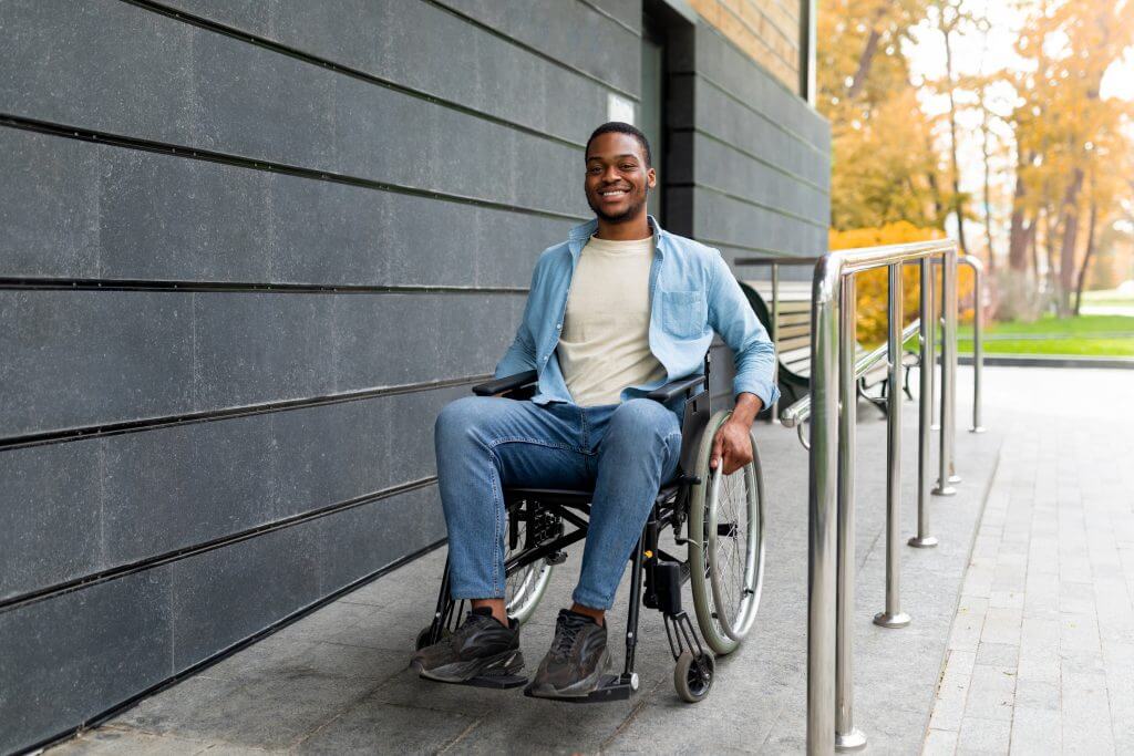 homme souriant en fauteuil roulant utilisant des installations adaptées aux personnes handicapées